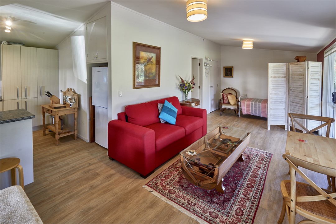 Cottage open plan lounge, red couch is a comfortab