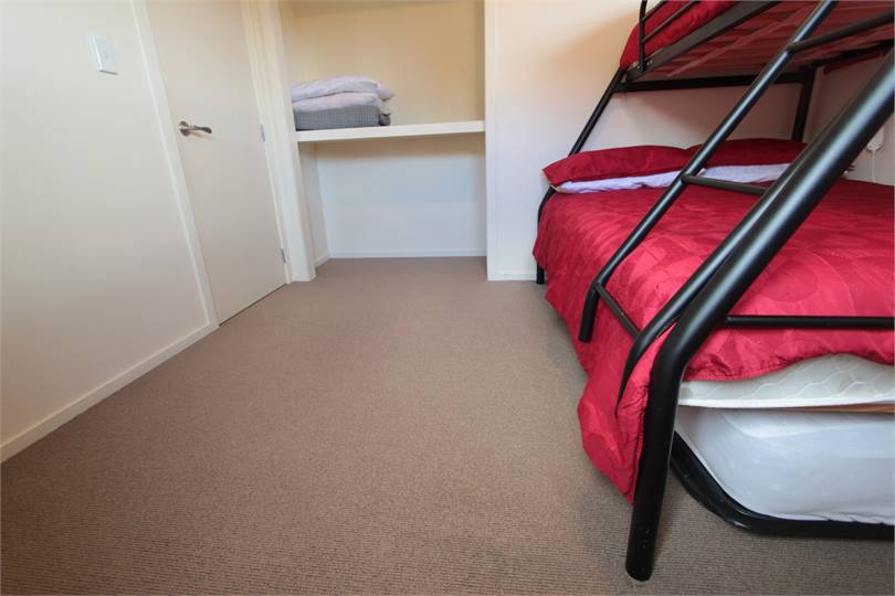 Trundler bed rolls away under double bunk bed.