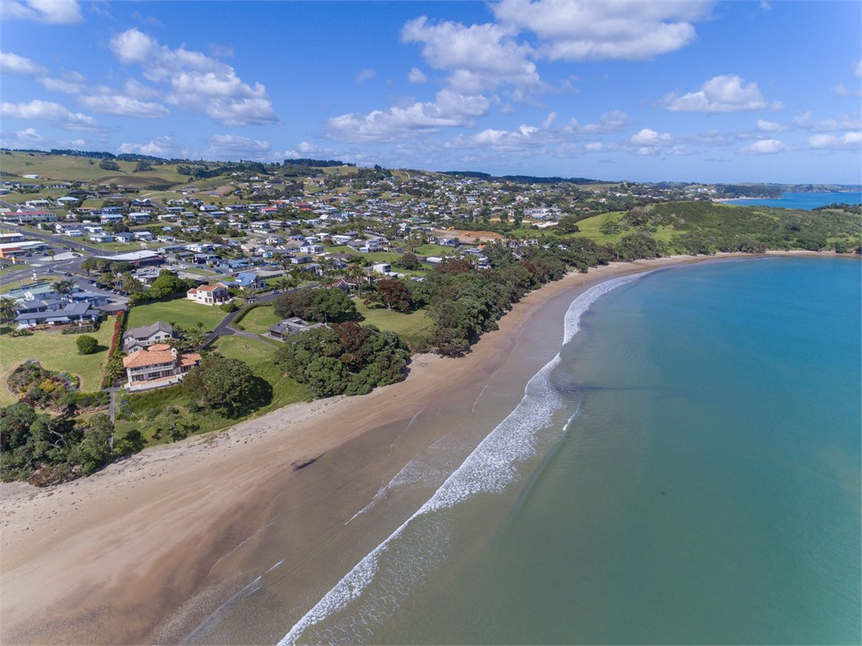 Shady Pohutukawa overhang the sand at Coopers.