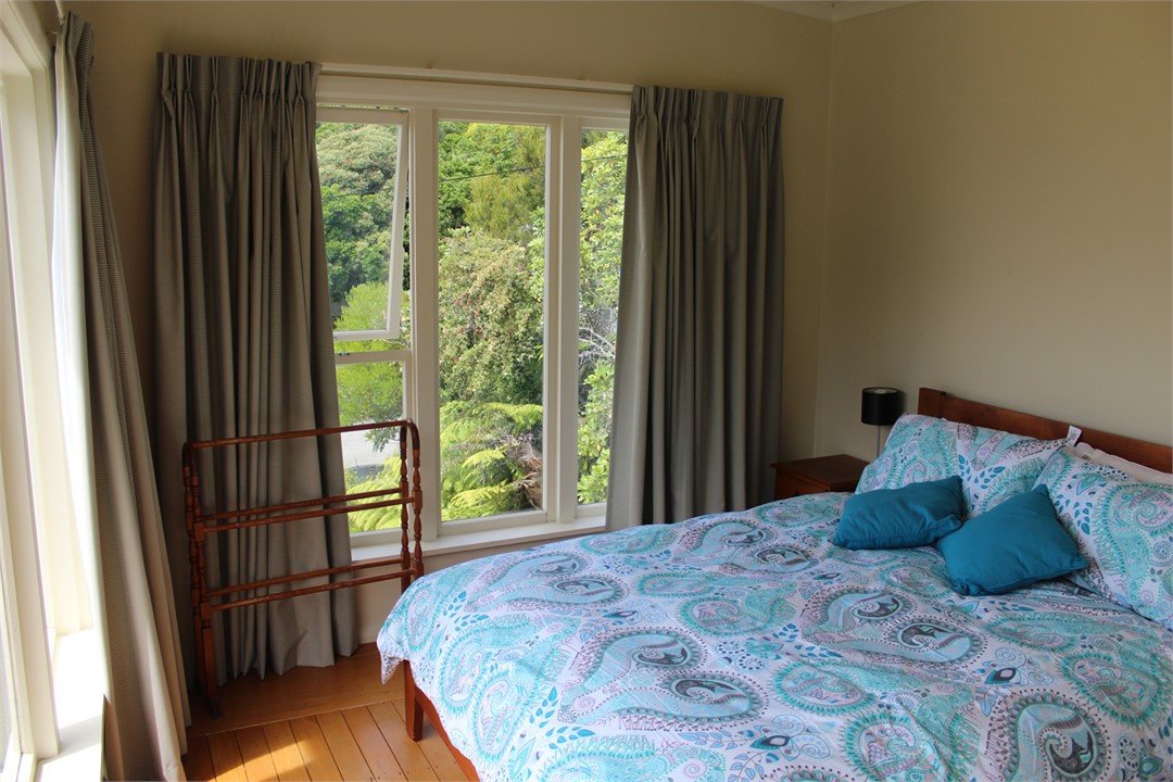 Queen size bed behind partition in open plan loung