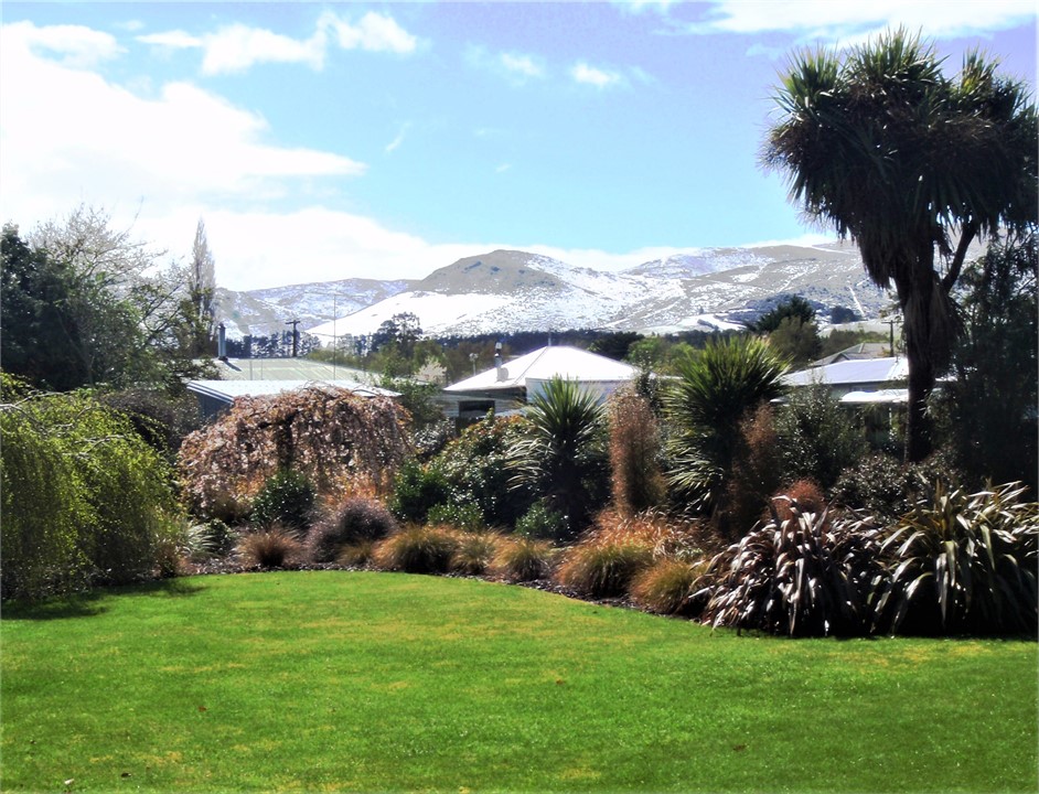 The front garden has a view of distant hills.