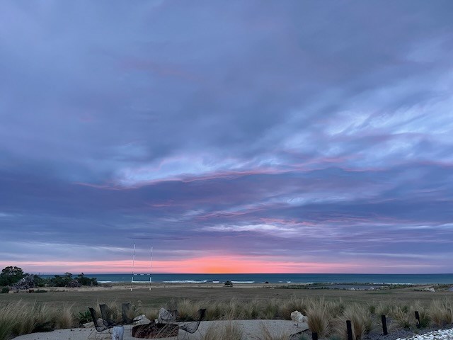 Fire pit at sunrise, rugby goal posts in backgroun