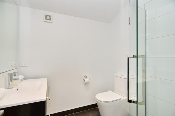 Clean bathroom with toilet, vanity mirror and show