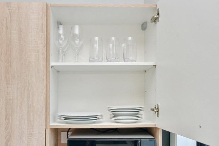 Plates and cups are located in the cupboard.