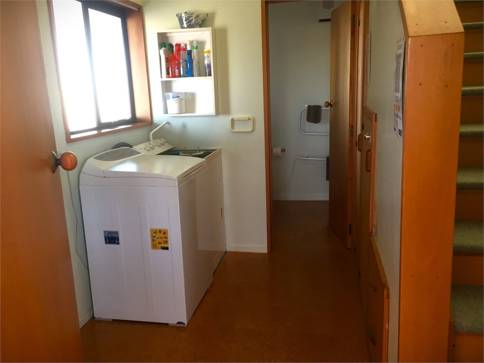 Laundry next to stairs, front door and bottom bath
